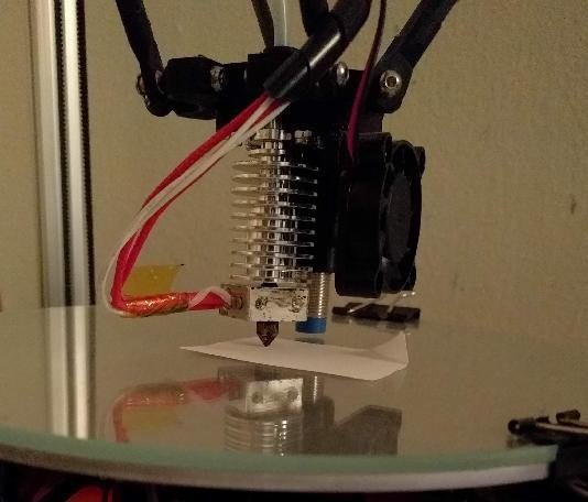 Ugello di una stampante 3D che esegue il test del foglio di carta per calibrare l'altezza dal piatto.