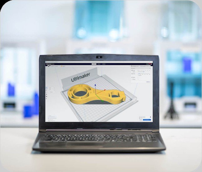 Schermata di UltiMaker Cura su un computer portatile che mostra un modello 3D giallo sul piano di stampa.