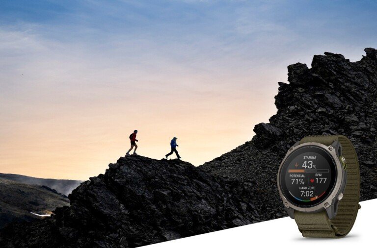 Smartwatch Garmin Enduro con cinturino verde e schermata delle prestazioni, con corridori sullo sfondo.
