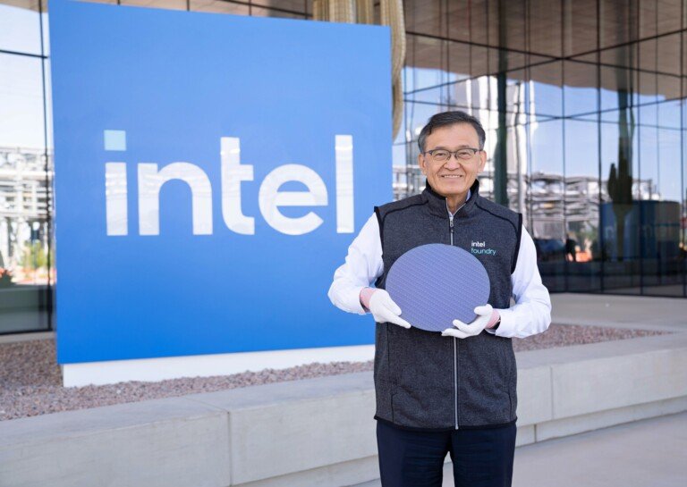 Un dirigente mostra un wafer di silicio davanti a un grande logo Intel.
